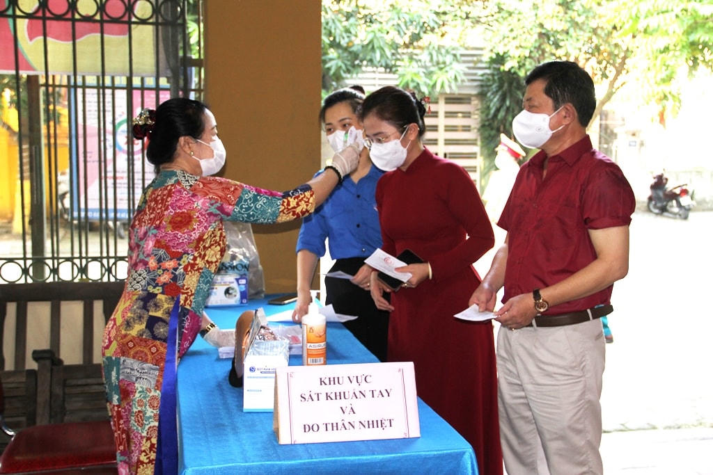  Thực hiện quy trình đo nhiệt độ, rửa tay sát khuẩn trước lúc vào khu vực bỏ phiếu (Ảnh: Điền Bắc).
