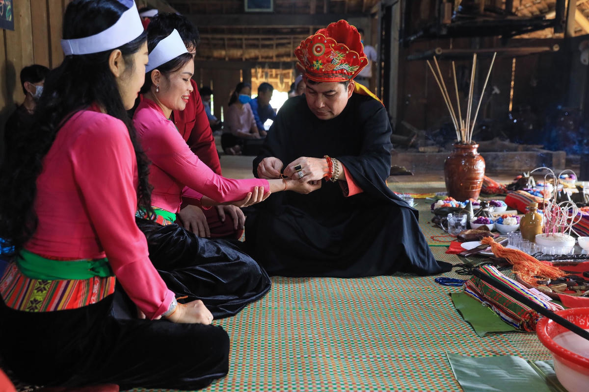 Thầy mo buộc chỉ tay cho các thành viên và du khách tới tham quan. Ảnh: Quang Vinh. 