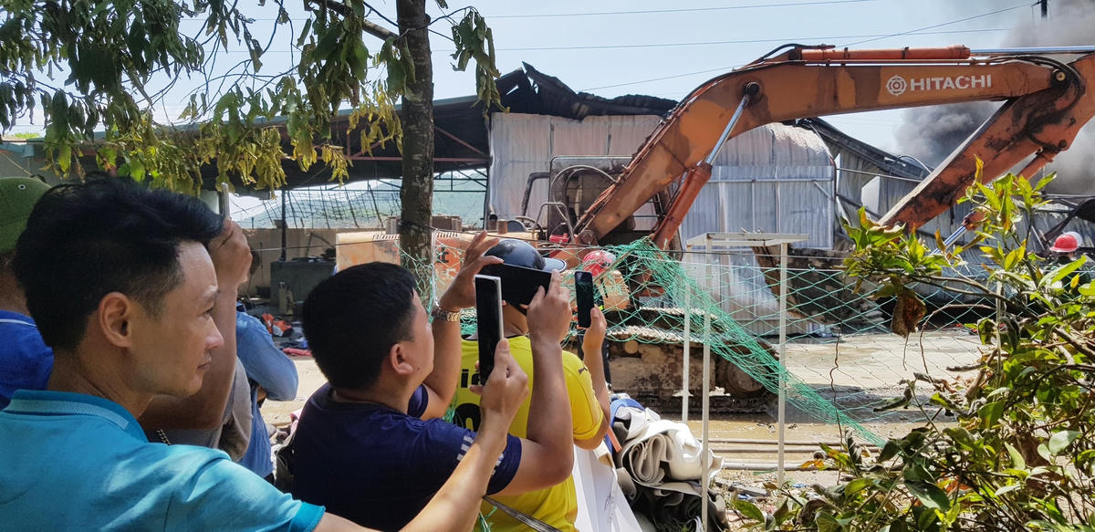 Bất chấp nắng và hơi nóng hầm hập từ đám cháy, đông đảo người dân hiếu kỳ vẫn “miệt mài” phát trực tiếp vụ cháy qua điện thoại.