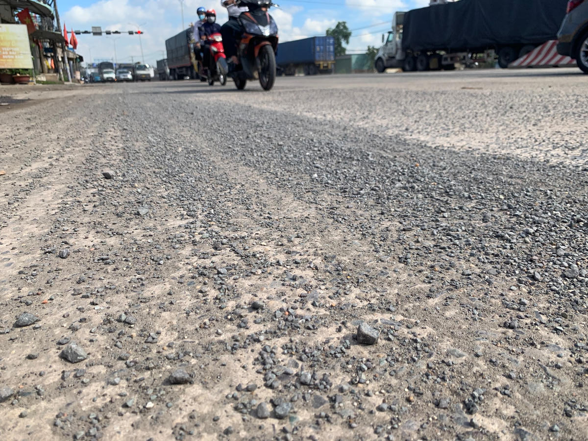 Đất và đá dăm do xe vận chuyện  làm rơi vãi xuống mặt đường góp phần làm tăng thêm lượng khói bụi.