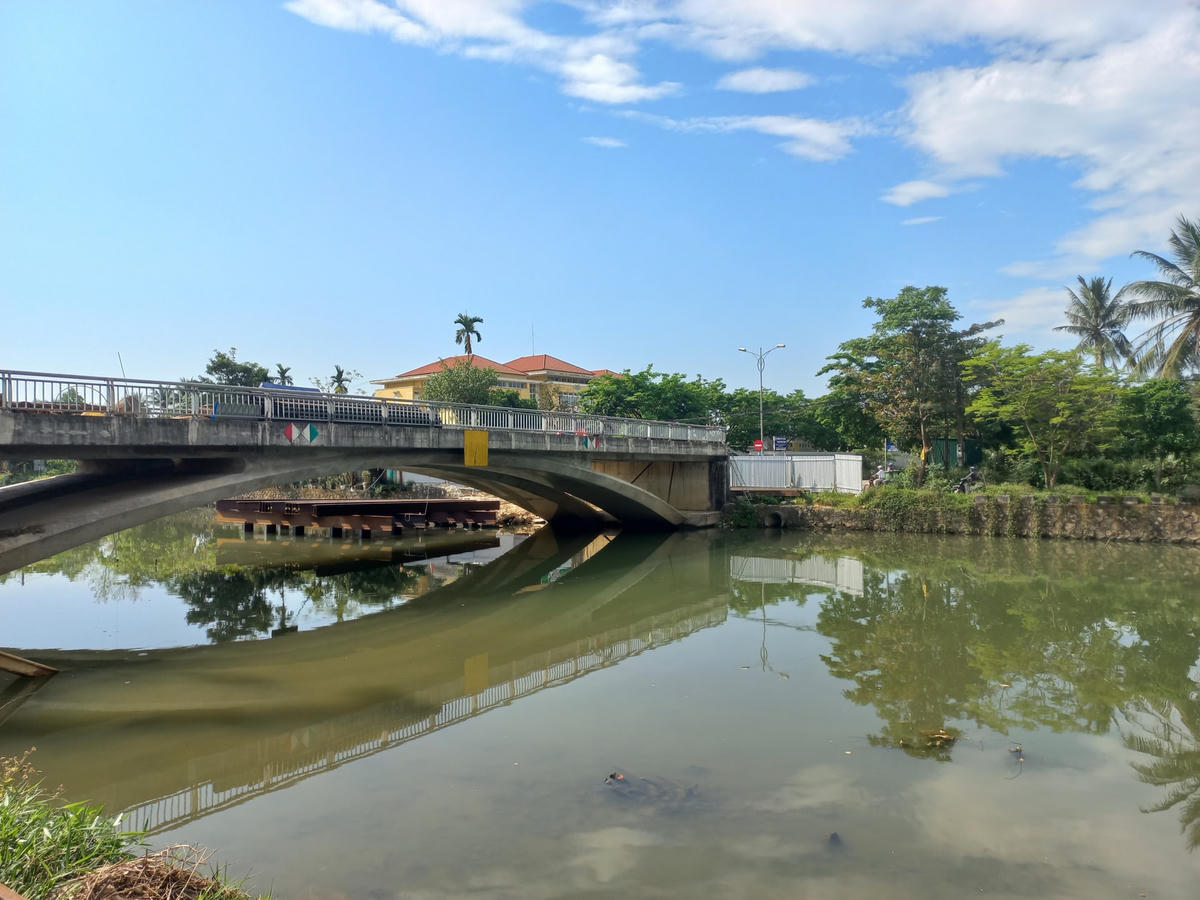 Dự án có tổng mức đầu tư 32 tỷ đồng, khởi công tháng 8/2017, thời gian thực hiện 3 năm kể từ ngày khởi công. Tuy nhiên, sau khi thi công cơ bản xong phần thô hạng mục cầu vào khoảng cuối năm 2018, nhưng lại không có đường dẫn để thông tuyến, khiến cây cầu này bị “treo” từ đó cho đến nay. 