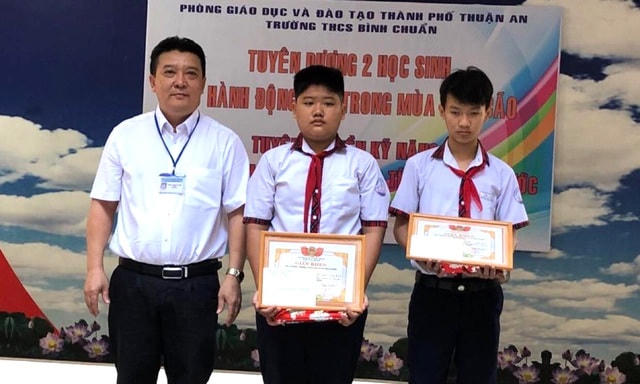 Hai em học sinh được nhà trường tuyên dương, khen thưởng.  
