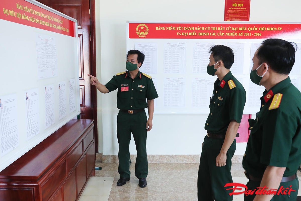 Các cử tri chuẩn bị thẻ cử tri và nghiên cứu thông tin về đại biểu Quốc hội khóa XV và đại biểu HĐND các cấp nhiệm kỳ 2021-2026. Ảnh: Quang Vinh. 