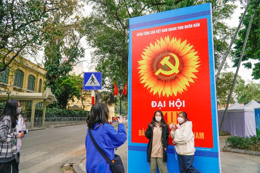 Các bạn trẻ thích thú chụp ảnh lưu lại kỷ niệm với tấm áp phích lớn. (Ảnh: Minh Hiếu/Vietnam+).
