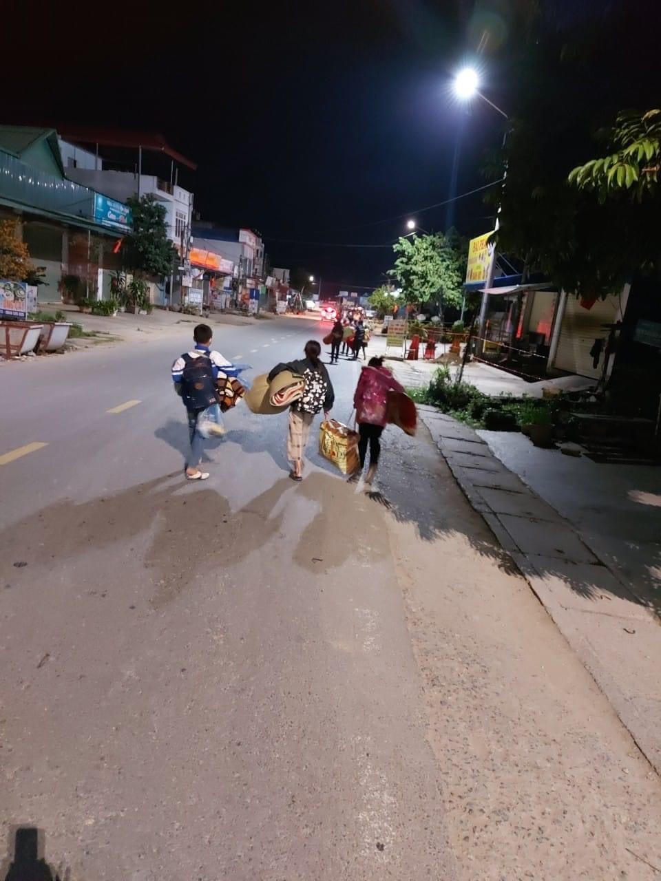 Các em học sinh tay ôm chiếu, chân đi dép lê đến khu cách ly.