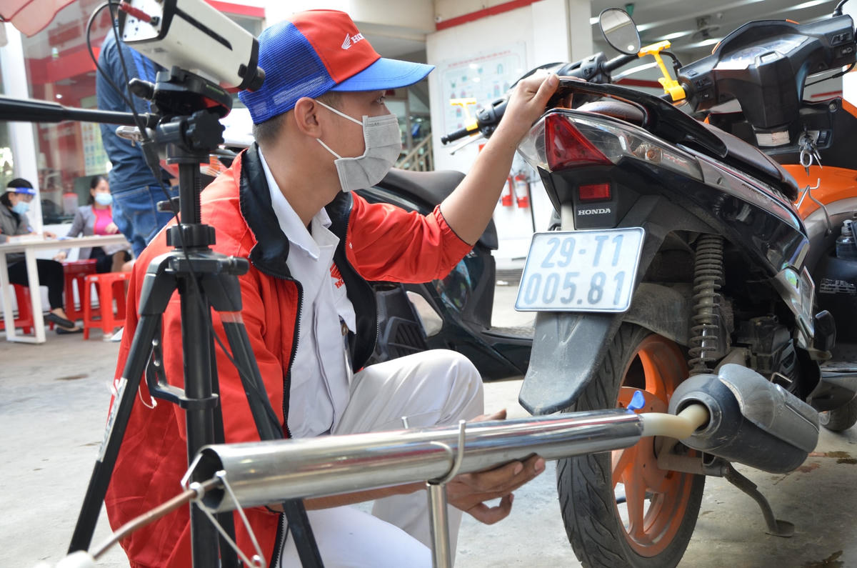 Nhân viên lắp đặt hệ thống đo kiểm khí thải xe máy. 