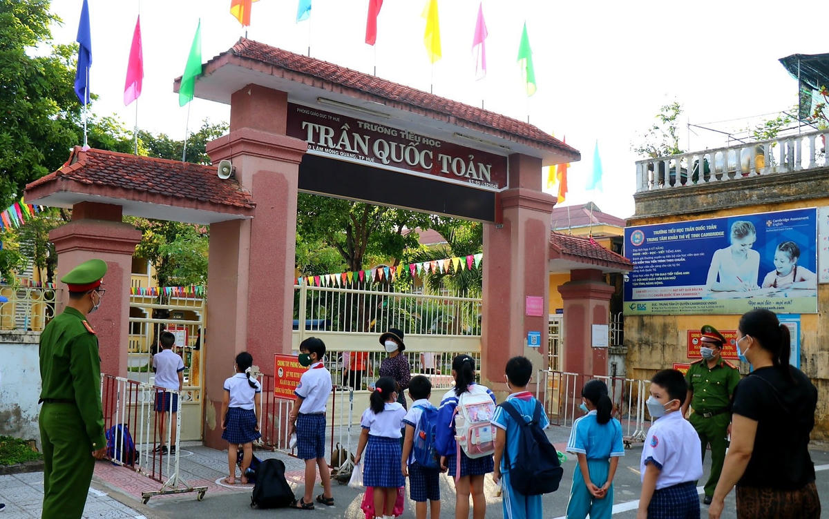 Trước cổng trường, lực lượng chức năng cùng với bảo vệ của nhà trường tổ chức phân luồng, đảm bảo an toàn giao thông và các biện pháp giãn cách đối với phụ huynh đưa con đến trường.