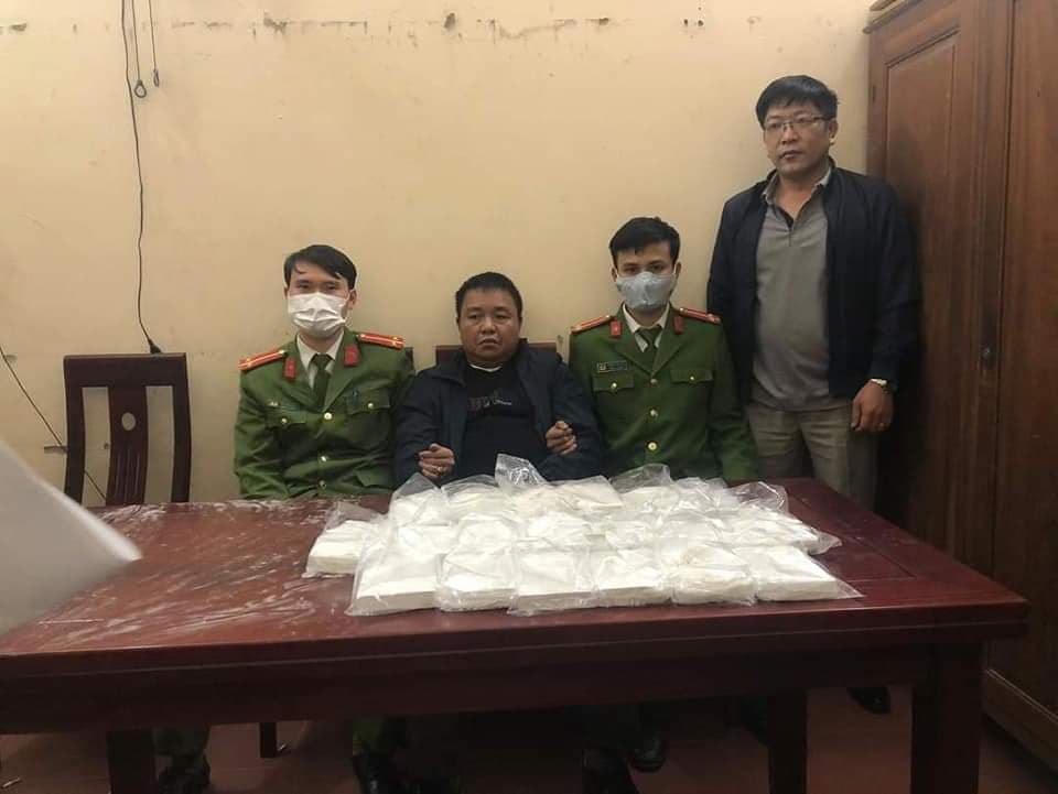 Đối tượng Minh (áo đen, ngồi giữa) cùng tang vật vụ án.