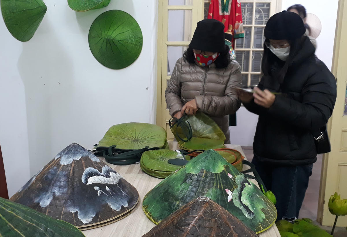 Du khách tham quan các sản phẩm như túi đựng và nón lá được làm từ lá sen.