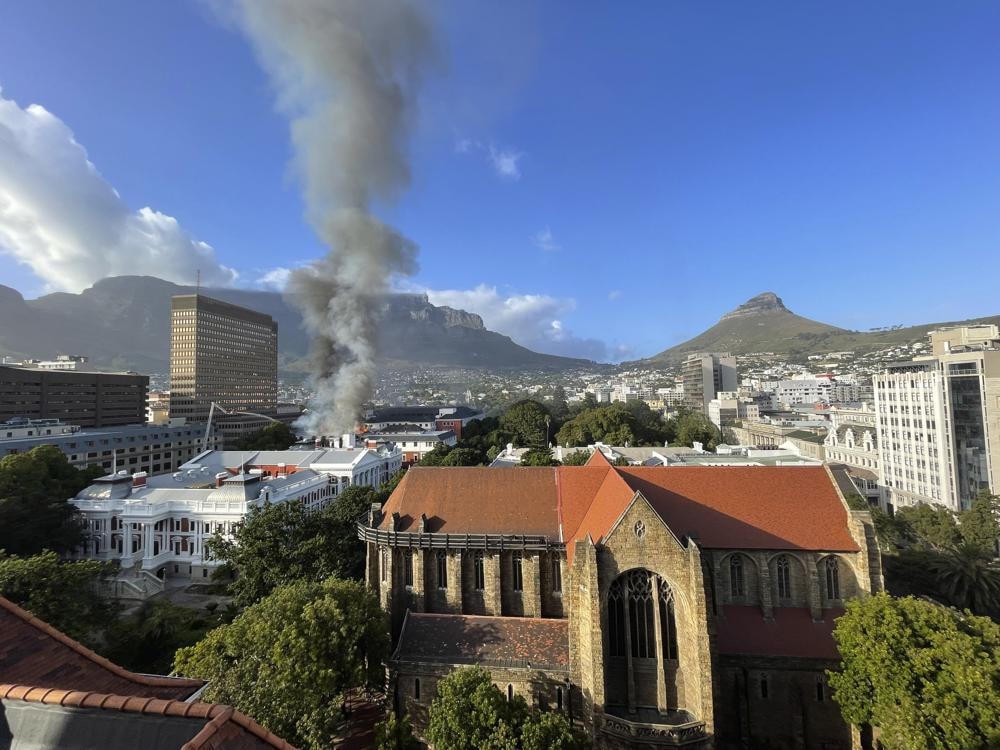 Một đám khói lớn bốc lên phía trên Tòa nhà Quốc hội, phía sau Nhà thờ St. George, ở Cape Town, Nam Phi. Ảnh: AP.