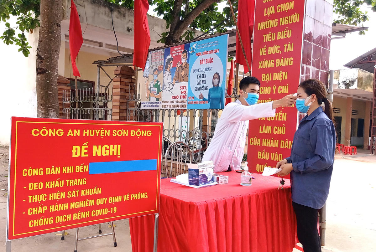 Cử tri được kiểm tra thân nhiệt, sát khuẩn tay trước khi vào khu vực bỏ phiếu.  