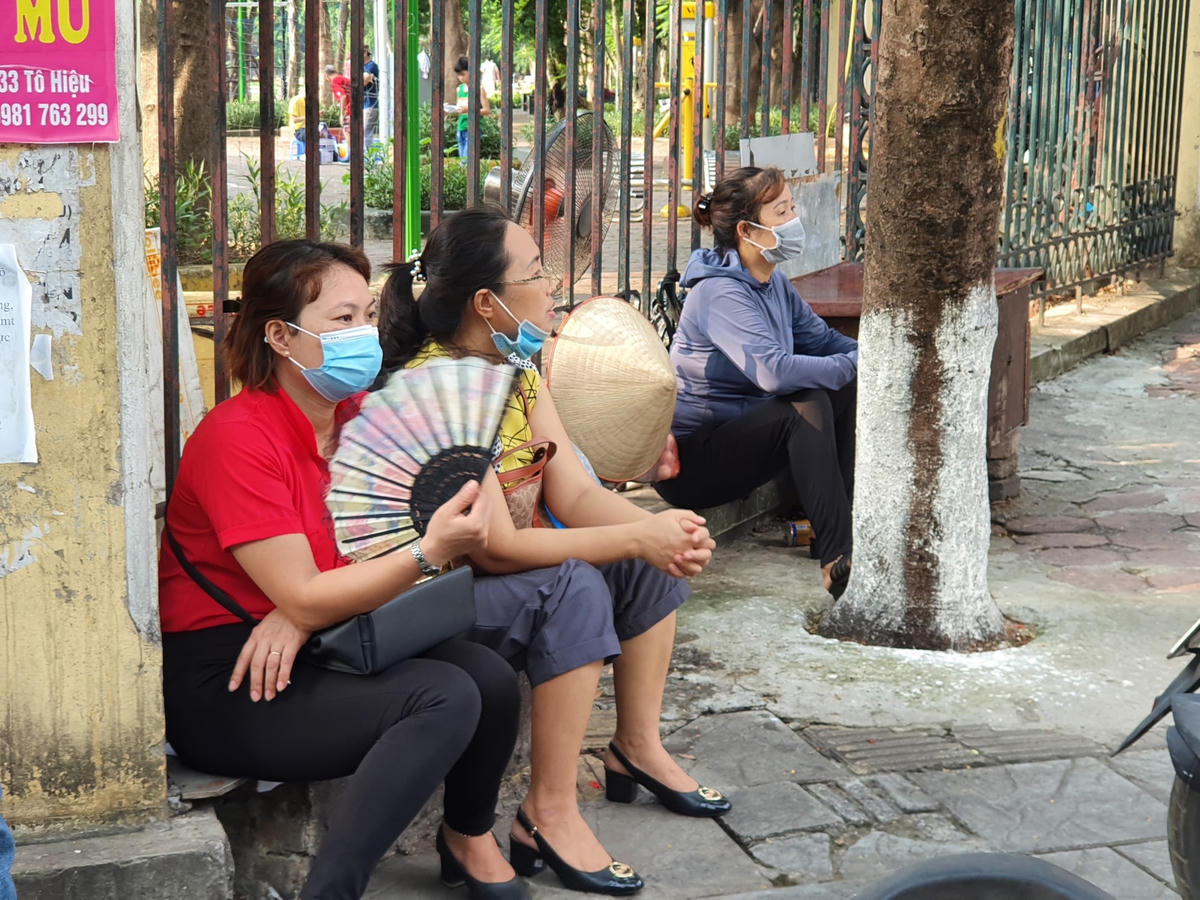 Một vài phụ huynh chọn chỗ ngồi dưới các bóng cây tránh nắng.