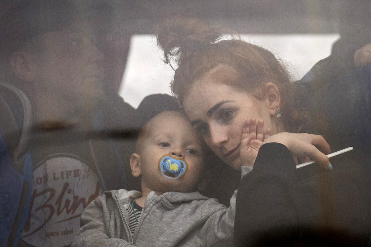 Người phụ nữ ôm đứa con trong chiếc xe buýt rời Kiev. Ảnh: Emilio Morenatti / AP FacebookTwitter.