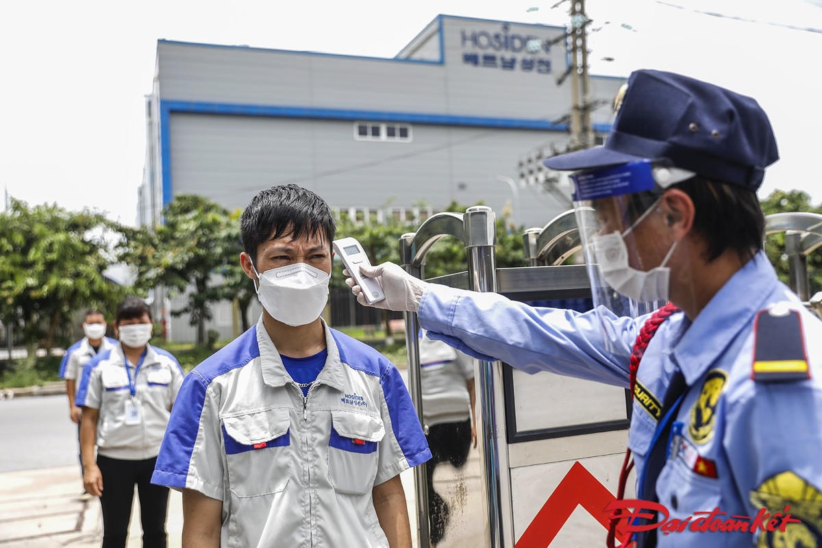 Một số doanh nghiệp tại KCN Quang Châu, Bắc Giang huy động số ít công nhân đến phân xưởng trong những ngày đầu. Công nhân xếp hàng thành từng nhóm nhỏ, thực hiện đo thân nhiệt. Ảnh: Quang Vinh. 