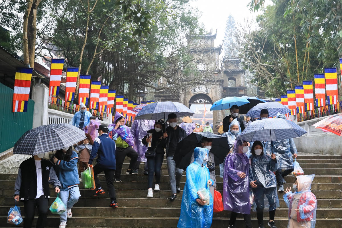 Trời mưa phùn nên du khách phải mặc áo mưa, che ô khi đến chùa Hương.