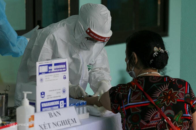 Nhân viên y tế phường Yên Hòa, quận Cầu Giấy, Hà Nội lấy mẫu máu test nhanh cho người về từ Đà Nẵng, ngày 30/7. Ảnh: Tất Định.  