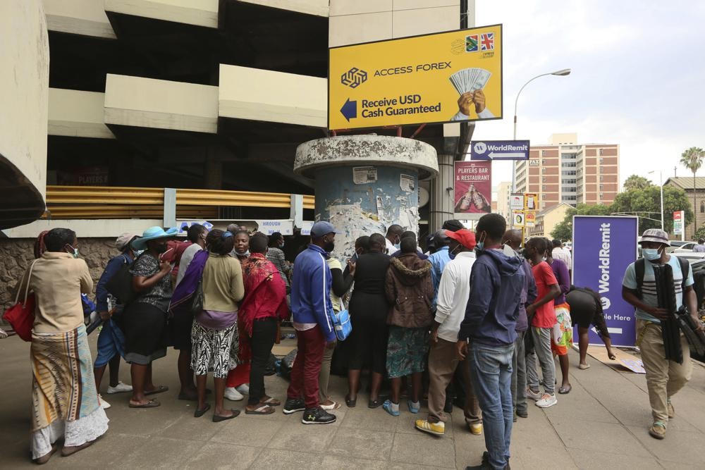 Những người dân tuyệt vọng chen chúc nhau bên ngoài sàn giao dịch ngoại tệ ở thủ đô Harare, Zimbabwe. Ảnh: AP.
