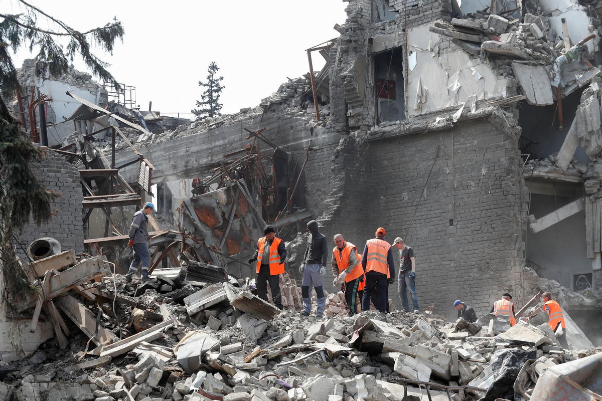 Người dân dọn dẹp các mảnh vỡ ở thành phố cảng phía nam Mariupol, Ukraine. Ảnh: Reuters.