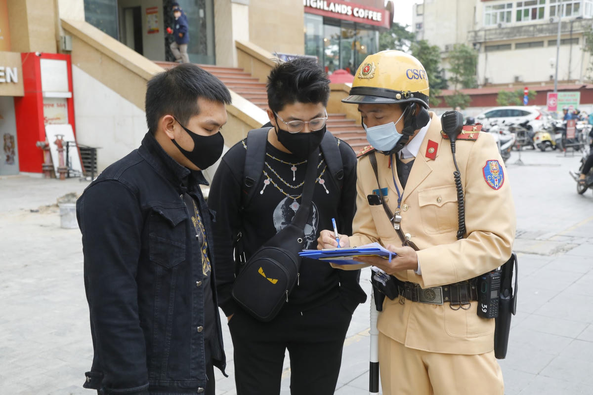 Cảnh sát giao thông lấy ý kiến của người làm chứng trong khi dán thông báo phạt nguội lên phương tiện dừng, đỗ sai quy định.Ảnh:Quang Vinh. 