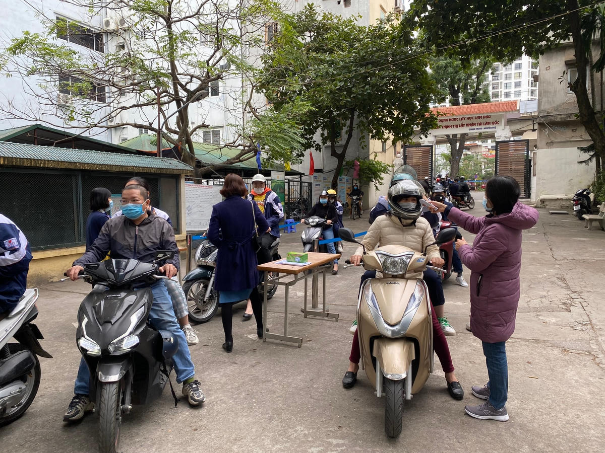 Phụ huynh và học sinh được đo thân nhiệt, sát khuẩn tay trước khi vào phòng chờ.