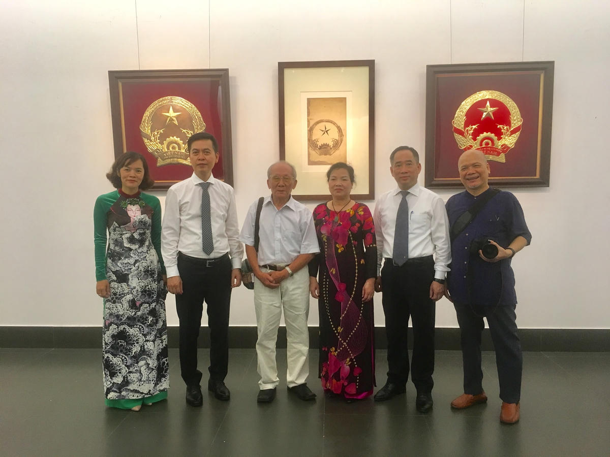 Đại diện BTC và gia đình, học trò họa sĩ Bùi Trang Chước chụp ảnh lưu niệm trước mẫu Quốc huy được chọn. 