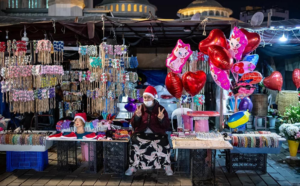 Một phụ nữ bán hàng rong làm dấu hiệu V (chiến thắng) trên Quảng trường Taksim ở Istanbul trong lễ đón năm mới ở Istanbul, Thổ Nhĩ Kỳ.