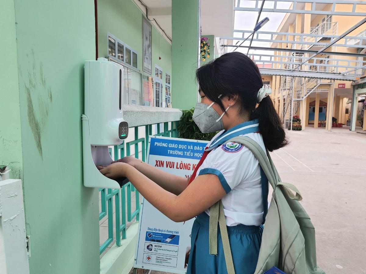 Học sinh đo thân nhiệt và sát khuẩn trước khi vào lớp. 