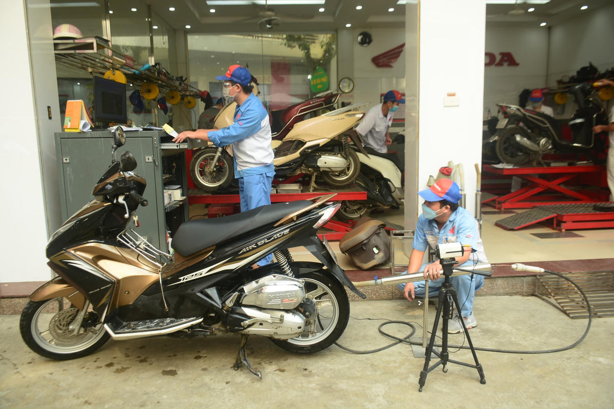 Xe máy đang được nhân viên kỹ thuật kiểm tra khí thải.