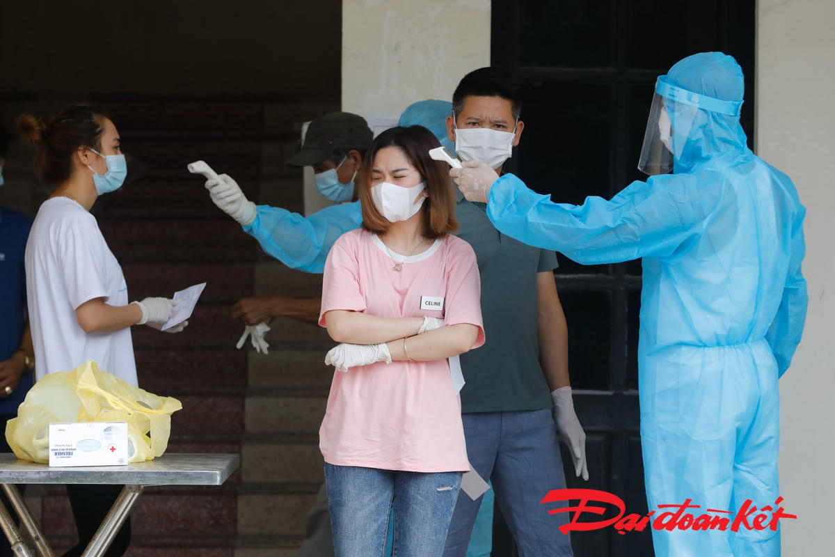 Các cử tri được đo thân nhiệt, đeo găng tay y tế trước khi vào khu vực bầu cử. Ảnh: Quang Vinh. 