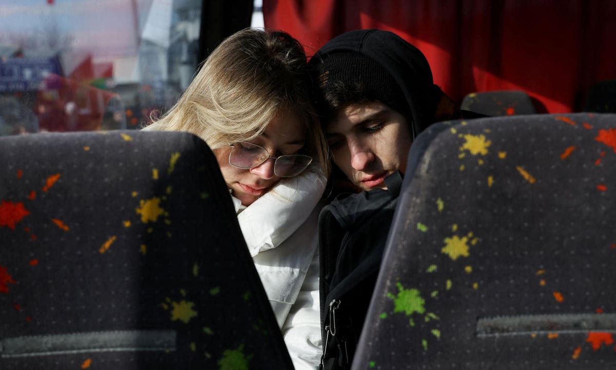 Một cặp đôi trẻ ngồi tựa vào nhau trên chiếc xe buýt tới biên giới giữa Ba Lan và Ukraine. Ảnh: Kacper Pempel / Reuters.