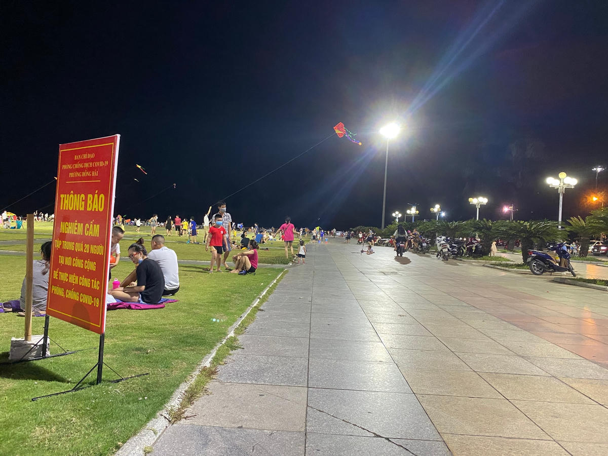 Biển thông báo của BCĐ phòng, chống dịch bệnh Covid-19 của thành phố Hạ Long đặt ngay ngoài công viên nhưng nhiều người vẫn vô tư tập trung ăn uống, vui chơi tại Quảng trường 30/10.