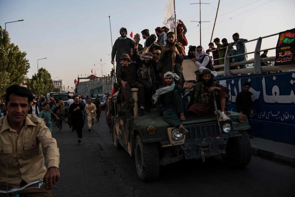Các chiến binh Taliban ngồi trên một chiếc Humvee bọc thép do Mỹ sản xuất, đi khắp các đường phố phía Tây Kabul trong khi người dân chạy xung quanh. (Ảnh: Andrew Quilty)