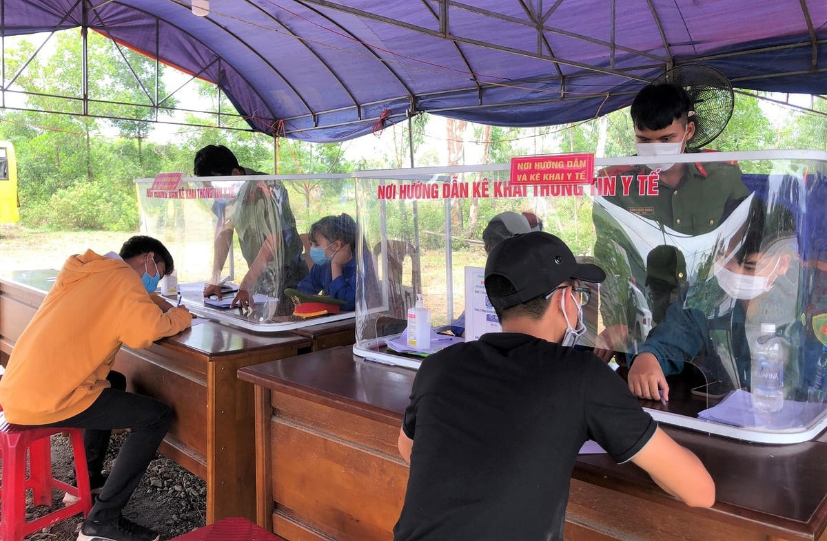 Người dân ngồi khoảng cách để khai báo y tế tại chốt kiểm dịch.