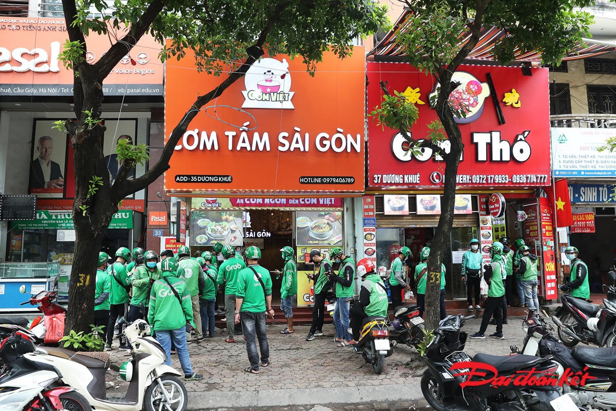Lượng đơn hàng "online" tăng đột biến, các tài xế công nghệ xếp hàng đợi nhận đồ. Ảnh: Quang Vinh.