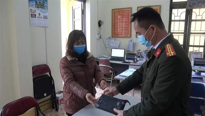 Chị Hoàng Hồng Lĩnh trao số tiền nhặt được cho Công an phường Tân Giang (Cao Bằng), đề nghị Công an xác minh, trao trả số tiền cho người đánh mất. (Ảnh: TTXVN).