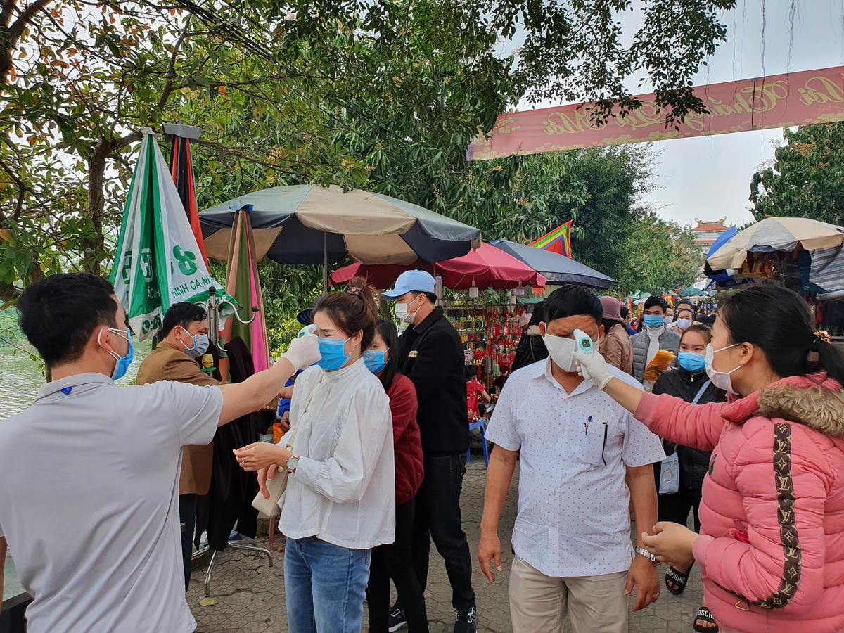 Cán bộ Ban QL đền Hoàng Mười đo thân nhiệt cho du khách trước lúc vào đền.