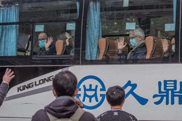 Các chuyên gia lên ô tô rời khách sạn cách ly ở Vũ Hán, trung Quốc. Ảnh: Reuters.