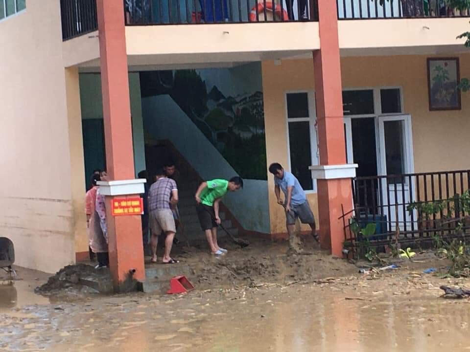 Mọi người đang quét dọn bùn đất ở phòng học.
