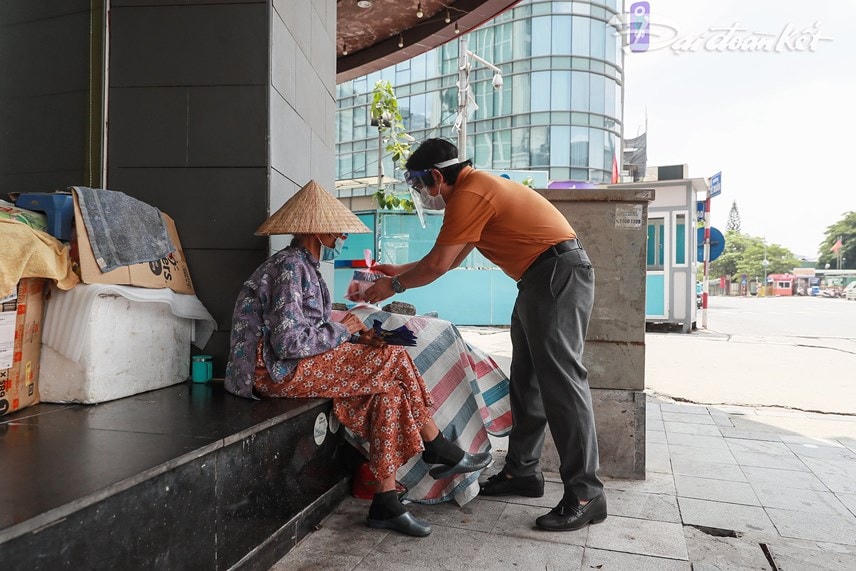 Báo Đại Đoàn Kết trao suất cơm cho một cụ già vô gia cư tại khu vực ga Hà Nội. Ảnh: Quang Vinh.   
