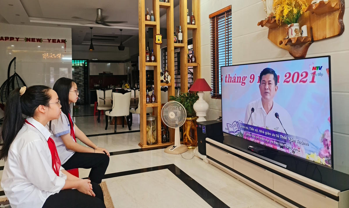 Chị em cháu LaNy, phường Đông Vĩnh (TP Vinh) chăm chú nghe phát biểu của người đứng đầu ngành giáo dục Nghệ An qua sóng truyền hình. (Ảnh: Phê Hoài).