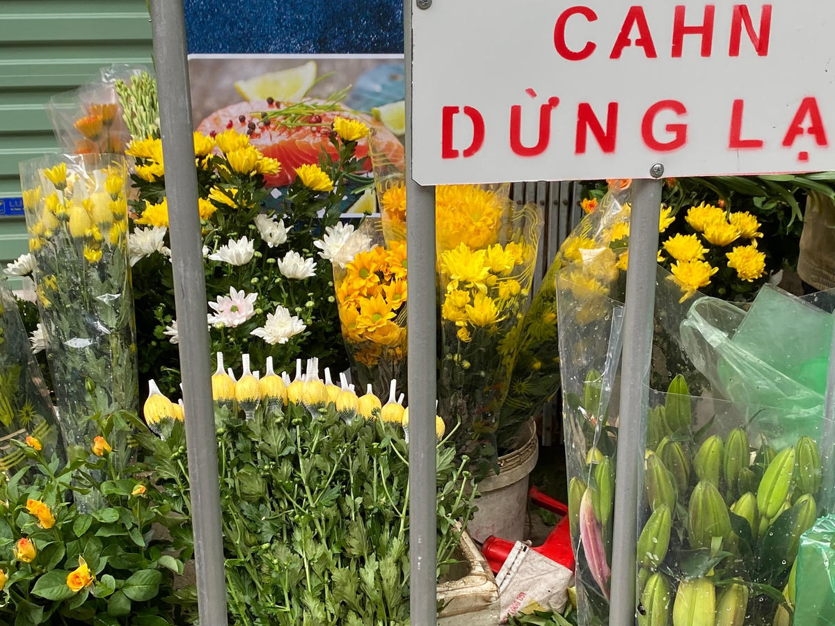Tại khu chợ Dịch Vọng (quận Cầu Giấy), các hàng hoa đã được bán trở lại, vẫn đảm bảo giữ khoảng cách giữa khách hàng và người bán qua hàng rào. 