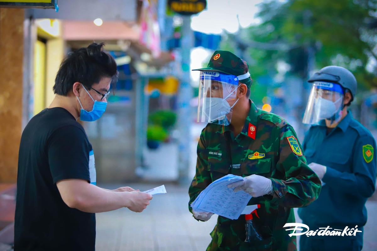Chiến sĩ tư vấn cho người dân về cách sử dụng phiếu đăng ký đi chợ thay và phương thức thanh toán.