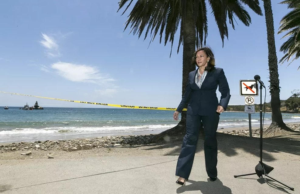 Bộ trưởng Tư pháp California Kamala Harris trong chuyến công tác dọn dẹp dầu tràn tại Bãi biển Refugio State, phía bắc Goleta, California, ngày 4/6/2015, mặc một bộ quần áo dài, giày cao gót và vòng cổ ngọc trai.  