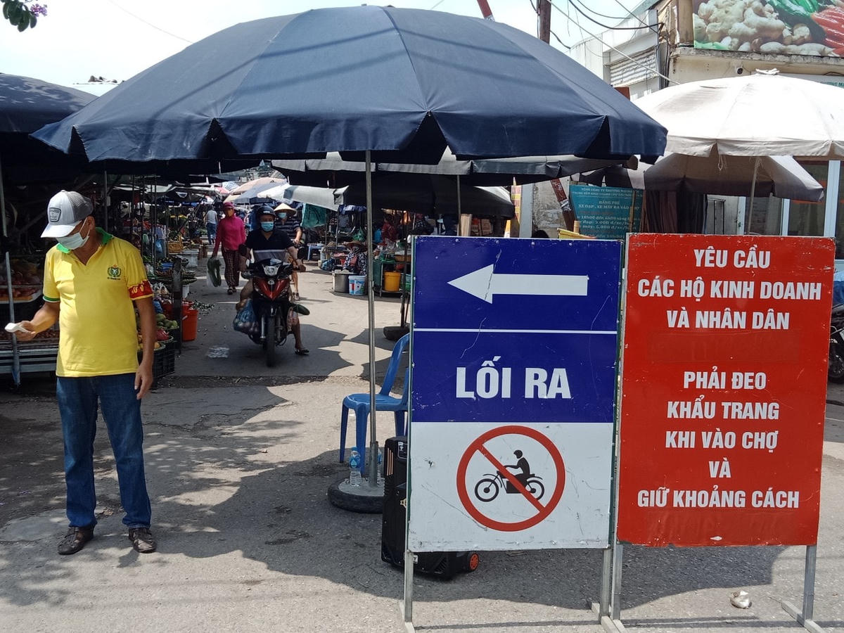 Chợ đầu mối phía Nam (Hoàng Mai, Hà Nội) tại cổng vào có biển báo phòng chống dịch, bảo vệ kiểm tra thân nhiệt những người vào chợ mua bán.