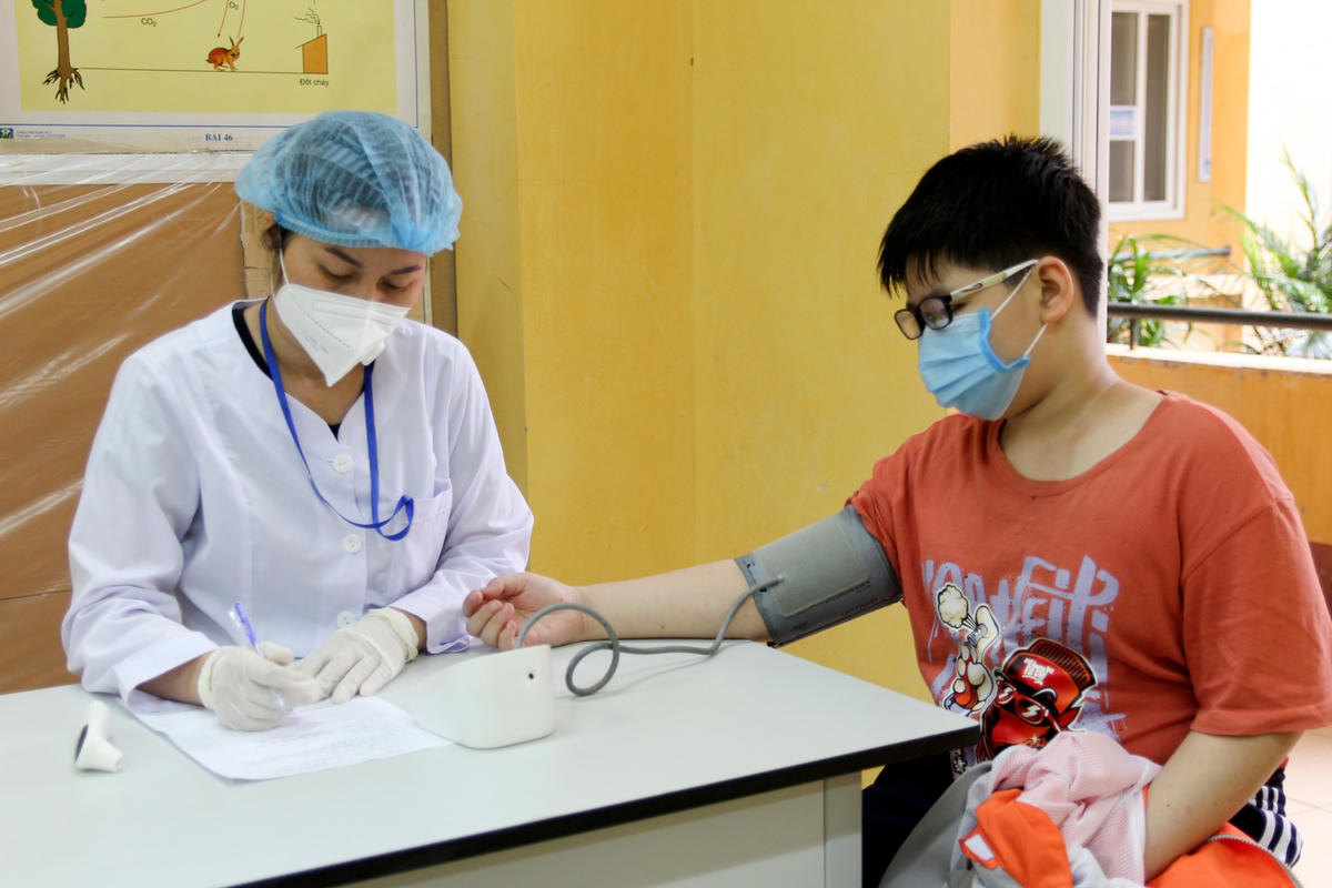 Học sinh được kiểm tra sức khỏe trước khi tiêm tại Trường THCS Nguyễn Trãi.
