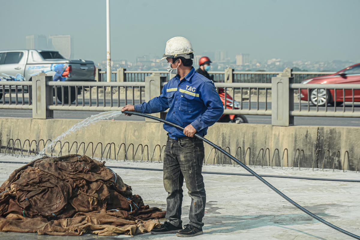 Sau khi mặt cầu được đổ bê tông, công nhân sẽ sử dụng các bao tải đã được nhúng nước trải đều trên bề mặt, giúp bê tông có độ bền cao hơn.