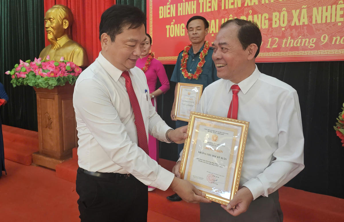 Bí thư xã Kỳ Xuân Hồ Huy Thành trao giấy chứng nhận tập thể điển hình tiên tiến Trường tiểu học Kỳ Xuân. Ảnh: Quang Lộc.