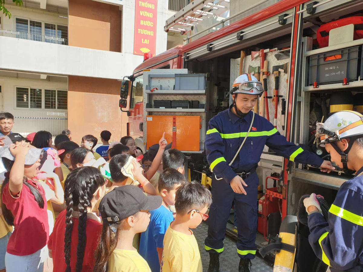 Cán bộ chiến sĩ PCCC hướng dẫn các dụng cụ chữa cháy trên xe chuyên dụng cho học sinh.
