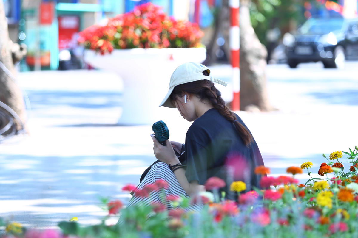 Nhiều bạn trẻ ngồi nghỉ ngơi, cạnh những bồn hoa đang khoe sắc.