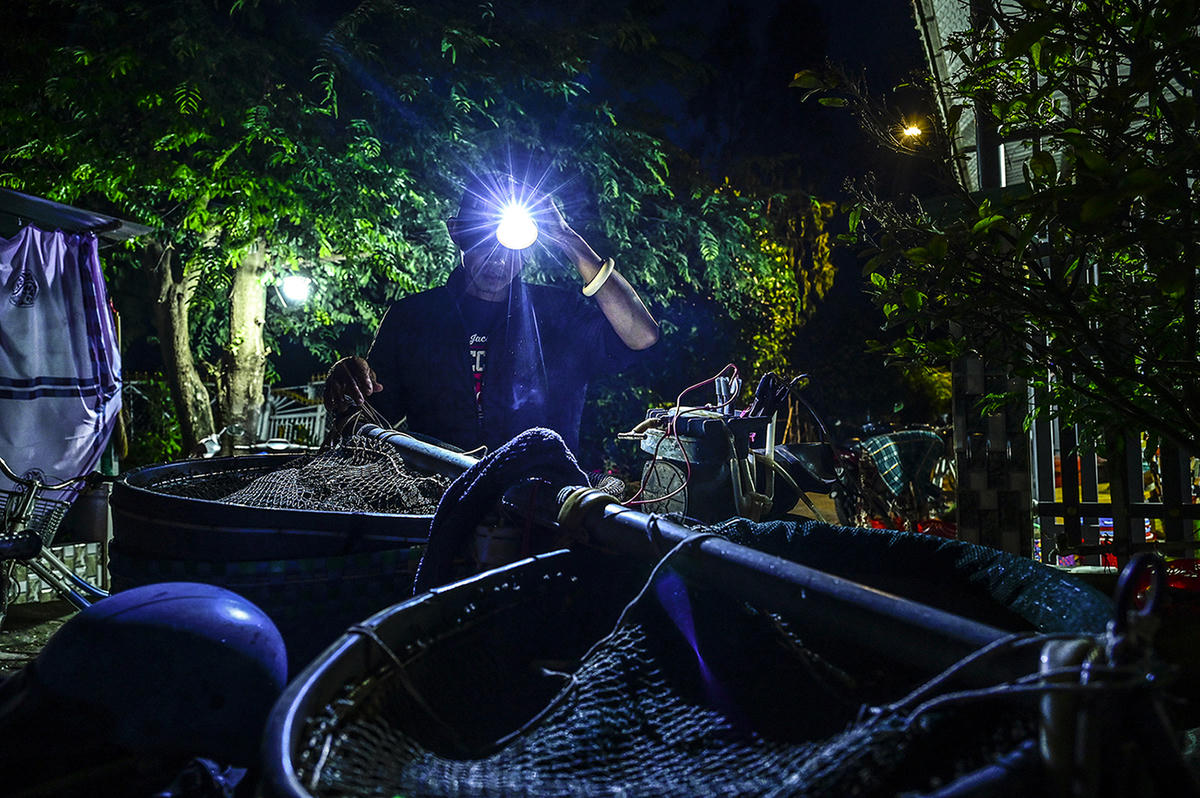 Một người dân rọi đèn pin đem cá ra chợ bán. Ảnh Nguyễn Minh
